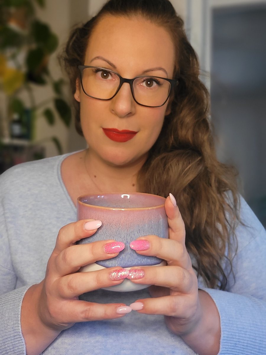 Alexandra hält eine rosa Kaffeetasse mit beiden Händen